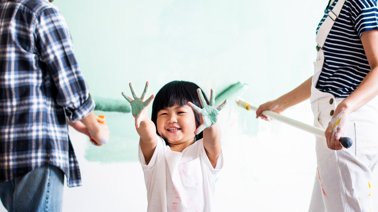 Đứa trẻ đang vui mừng sơn sửa lại ngôi nhà cùng cha mẹ; hình ảnh sử dụng cho trang vay thế chấp bất động sản HSBC Việt Nam