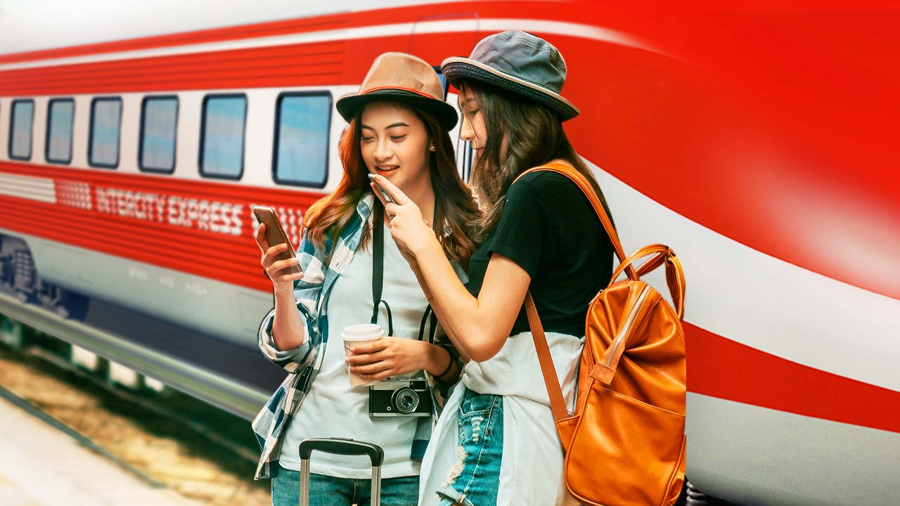 Two female travellers using mobile phone outside of a train; image used for HSBC Vietnam Mobile Banking page
