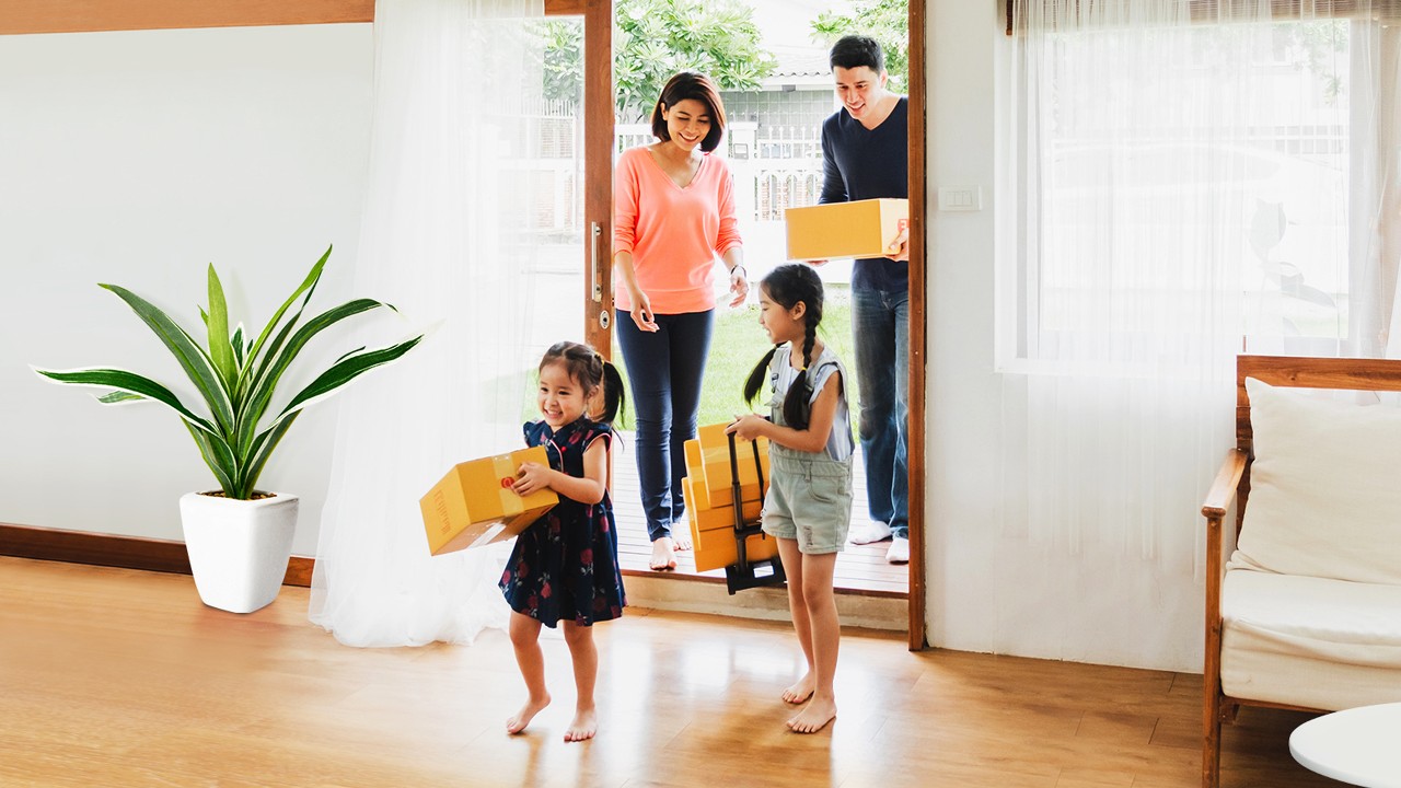 Một gia đình bốn người vào một ngôi nhà mang theo một số hộp để di chuyển đồ đạc; hình ảnh được sử dụng cho Trang Cho Vay Thế Chấp Mua Nhà Của HSBC Việt Nam.